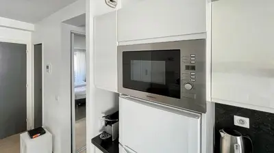 a kitchen with a microwave in a white wall at 2 Room modern, terrace and Parking in Cannes