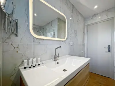 a white bathroom with a sink and a mirror at Deluxe 2 bedroom apartment in Cannes