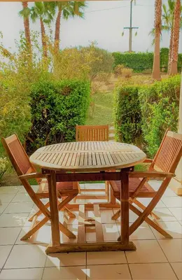 a wooden picnic table with two chairs around it at Appartement Bord de Mer 4 pers / 2 Piscines in Cannes