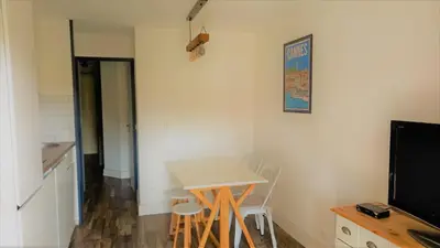 a kitchen with a table and chairs and a television at Appartement Bord de Mer 4 pers / 2 Piscines in Cannes