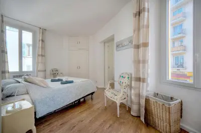 a bedroom with a bed and a chair and a window at Le Cal-3 Pièces-2 min Plage-VCA in Cannes