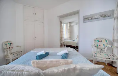 a white bedroom with a bed and two chairs at Le Cal-3 Pièces-2 min Plage-VCA in Cannes