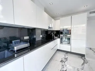 a white kitchen with black counter tops and appliances at Modern 3 bedroom flat with balcony in Cannes