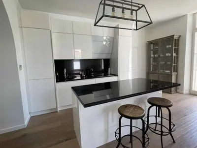 a kitchen with a black counter and two stools at Beautifully renovated 3 bedroom apartment in the heart of Cannes in Cannes