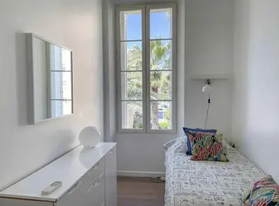 a white room with a bed and two windows at Beautifully renovated 3 bedroom apartment in the heart of Cannes in Cannes