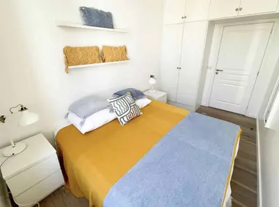 a small bedroom with a bed with a yellow blanket at Beautifully renovated 3 bedroom apartment in the heart of Cannes in Cannes