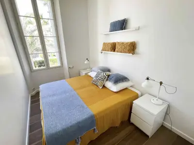 a bedroom with a bed with a yellow and blue blanket at Beautifully renovated 3 bedroom apartment in the heart of Cannes in Cannes