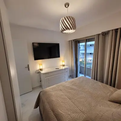 a bedroom with a bed and a flat screen tv at Bell Appartement Cannes in Cannes