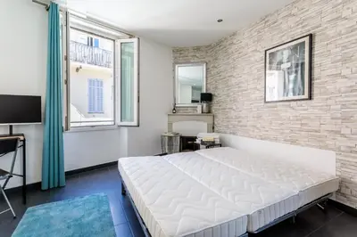 a bedroom with a white bed and a brick wall at Les Suisses Apartment Zentral in der schönen Altstadt von Le Suquet 5 min zum Strand WLAN in Cannes