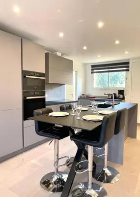 a kitchen with a black table with chairs and a counter at Le Cèdre Magnifique Appartement à Cannes in Cannes
