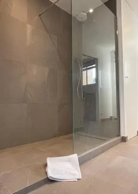 a bathroom with a glass shower with a towel on the floor at Le Cèdre Magnifique Appartement à Cannes in Cannes