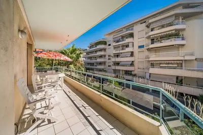 a balcony with chairs and an umbrella and a building at Pleasant 2 bedroom close to the center of Cannes in Cannes
