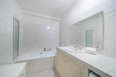 a white bathroom with a tub and a sink and a mirror at Pleasant 2 bedroom close to the center of Cannes in Cannes