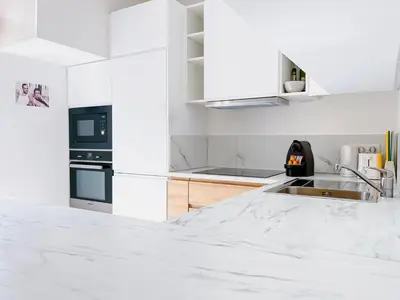 a white kitchen with marble counter tops and appliances at Le canopée - Cozy Suquet Cannes Centre in Cannes
