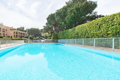 an empty swimming pool with a fence and trees at villa dans résidence à Cannes in Cannes