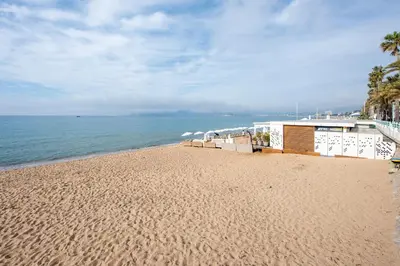 a sandy beach with a building and the ocean at Appartement Dollia - Welkeys in Cannes