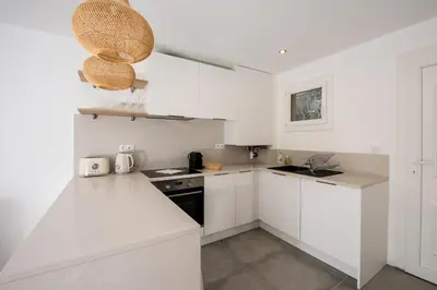 a white kitchen with white cabinets and a sink at Appartement Dollia - Welkeys in Cannes