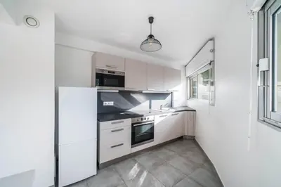 a white kitchen with white cabinets and a window at Nice one bedroom in the heart of Cannes in Cannes