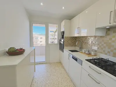 a kitchen with white cabinets and a sink and a window at Le charme de Cannes in Cannes