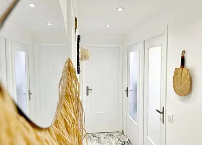 a hallway with white doors and a mirror at Le charme de Cannes in Cannes