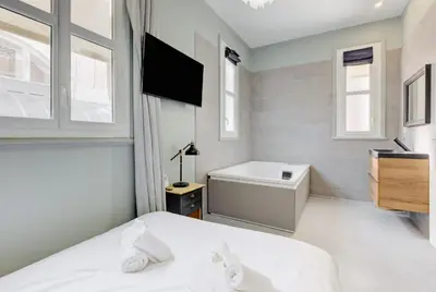 a bedroom with a bed and a tub and a television at Le Palais Beausite - Palais à Cannes in Cannes