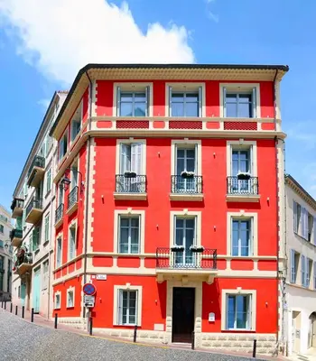 a red building with balconies on a street at Apartments in the heart of Cannes in Cannes