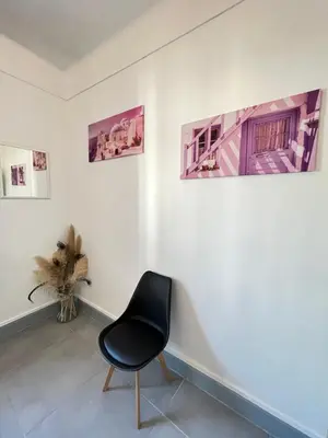 a black chair in a room with paintings on the wall at Appartement 3 pièces GREEN ART **** in Le Cannet