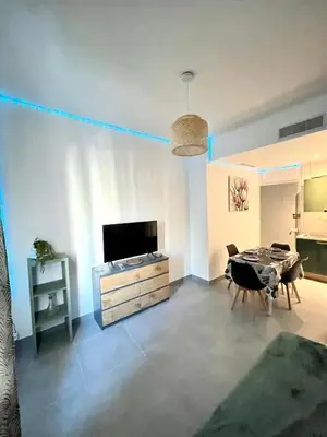 a living room with a dining table and a television at Appartement 3 pièces GREEN ART **** in Le Cannet
