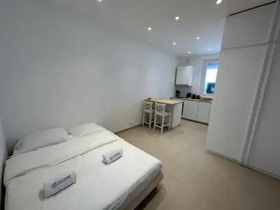 a white bedroom with a bed and a kitchen at C073-Studio neuf et lumineux au carre d'or Croisette in Cannes