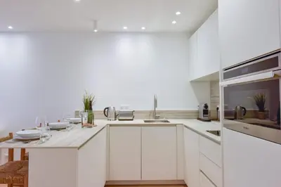 a white kitchen with white cabinets and a sink at Upscale 1-Br apartment 100 meter from the Palais des Festivals in Cannes