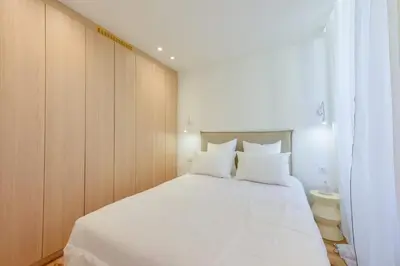 a bedroom with a large white bed with wooden cabinets at Upscale 1-Br apartment 100 meter from the Palais des Festivals in Cannes
