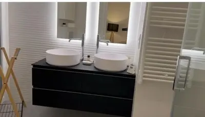 a bathroom with two sinks on a black counter with a mirror at M.M.R. Gioma in Cannes