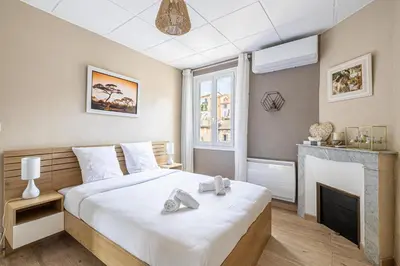 a bedroom with a large bed and a fireplace at Beau 3 pièces à 500m du Palais des Festival in Cannes