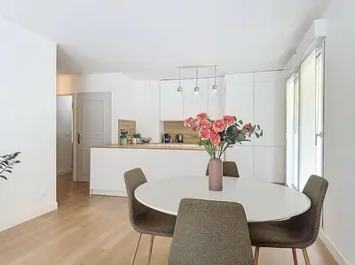 a white kitchen with a table with a vase of flowers at Agencia Superbe appartement 2 chambres in Cannes