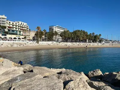 a beach with rocks in the water and buildings at Grand 2 pieces- Marche Forville in Cannes