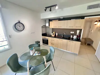 a kitchen with a table and chairs and a clock on the wall at B035 Magnifique appartement neuf a deux pas du centre in Cannes