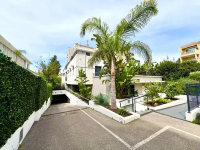an apartment building with a palm tree in a parking lot at B035 Magnifique appartement neuf a deux pas du centre in Cannes