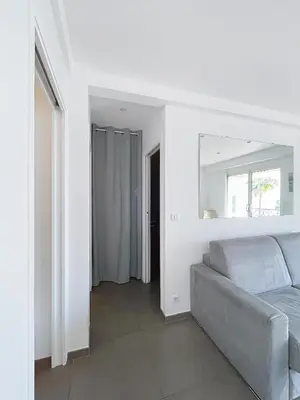 a living room with a gray couch and a mirror at Le Croisette - 4 pers - Front de mer - 15 min Palais in Cannes