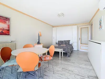 a living room with a table and chairs and a couch at Le Montfleury - Studio 28m2 - Vue mer - Centre in Cannes