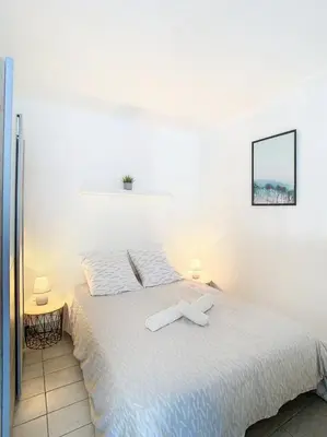 a bedroom with a bed with a cross on it at Le Palladium - Studio - 10mn Palais - Climatisé in Cannes