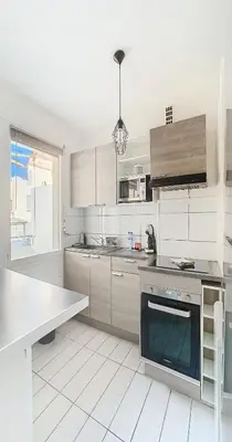 a white kitchen with a sink and a stove at Le Palladium - Studio - 10mn Palais - Climatisé in Cannes