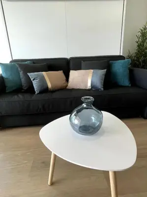 a glass vase on a white table in front of a couch at Appartement Pépite à Cannes in Cannes
