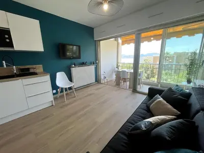 a living room with a couch and a kitchen with a table at Appartement Pépite à Cannes in Cannes