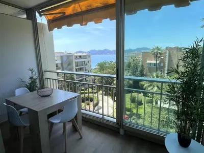 a balcony with a table and chairs and a large window at Appartement Pépite à Cannes in Cannes