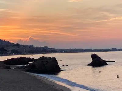 a beach with rocks in the water at sunset at Cannes Beach Access, Private Room in Shared 3-Bedroom Apartment, Private Bathroom, Living Room with Sea View Suite Parentale salle de bain privée accès plages & vue mer du salon dans appartement partagé chez l'habitant in Cannes