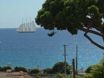 a sail boat in the water with a boat in the ocean at Cannes Beach Access, Private Room in Shared 3-Bedroom Apartment, Private Bathroom, Living Room with Sea View Suite Parentale salle de bain privée accès plages & vue mer du salon dans appartement partagé chez l'habitant in Cannes