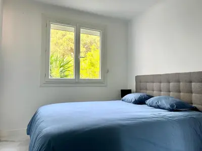 a bed with two blue pillows and a window at Superbe appartement à Cannes / 3 chambres in Cannes