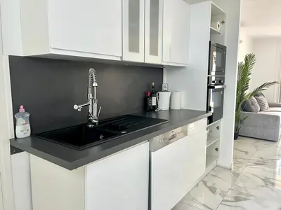 a kitchen with white cabinets and a black sink at Superbe appartement à Cannes / 3 chambres in Cannes