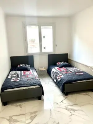 a bedroom with two beds and two windows at Superbe appartement à Cannes / 3 chambres in Cannes