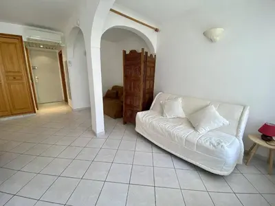 a living room with a white couch and a table at Cannes proche croisette - Studio balcon vue jardin in Cannes
